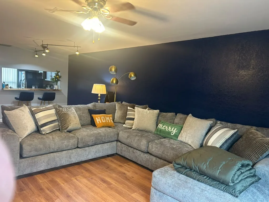A post-construction clean living room with a navy accent wall, after the remodel